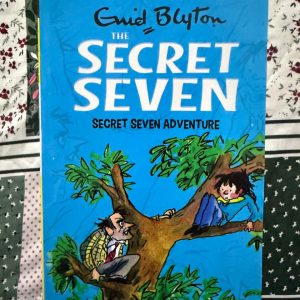 Used Book - Enid Blyton - The Secret Seven Adventure - Hachette India - In The Secret Seven Adventure, Enid Blyton brilliantly balances wholesome suspense with youthful ingenuity. After witnessing a robbery, the Seven must decode clues to catch the culprits. It’s a nostalgic triumph that celebrates bravery and the thrill of the chase, proving that no mystery is too big for loyal friends.