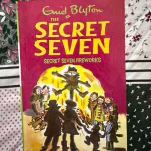 Used Book - Enid Blyton - Secret Seven Fireworks - Hachette India - Secret Seven Fireworks is an explosive addition to the series, blending seasonal excitement with a high-stakes mystery. Blyton brilliantly uses the backdrop of Guy Fawkes Night to heighten the tension as the Seven track down a gang of thieves. It’s a vivid, atmospheric tale that celebrates vigilance and community spirit.