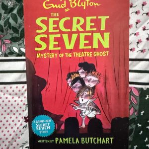 Used Book - Enid Blyton - The Secret Seven - Mystery of The Theatre Ghost - Pamela Butchart - Hachette India - Pamela Butchart delivers a spirited encore with Mystery of the Theatre Ghost. By blending a classic eerie setting with the Secret Seven's signature teamwork, she creates an atmospheric page-turner. It’s a wonderful homage that respects the original series' legacy while injecting a fresh, humorous energy that keeps the mystery alive.