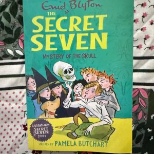 Used Book - Enid Blyton - The Secret Seven - Mystery of The Skull Ghost - Pamela Butchart - Hachette India - Pamela Butchart breathes fresh life into the iconic society with Mystery of the Skull. Balancing classic nostalgia with a modern, high-energy pace, she maintains the charm of Enid Blyton’s world while adding spooky atmosphere and clever humor. It’s a brilliant, spooky revival that proves the Seven's adventures are truly timeless.
