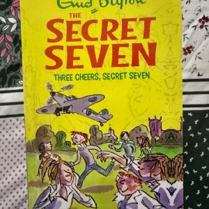 Used Book - Enid Blyton - Three Cheers Secret Seven - Hachette India - Three Cheers Secret Seven is a delightful mystery that perfectly captures the essence of childhood adventure. Enid Blyton weaves a suspenseful tale of hidden clues and clever detective work, proving that no secret is safe from Peter and his team. It’s a nostalgic, fast-paced classic that celebrates friendship and bravery.