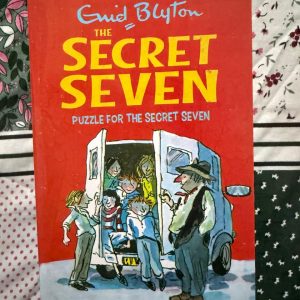 Used Book - Enid Blyton - Puzzle For The Secret Seven - Hachette India - Puzzle for the Secret Seven is a gripping blend of empathy and intrigue. When a house fire leads to a puzzling theft, Blyton masterfully balances a somber mystery with the group’s signature resourcefulness. It’s a standout entry that highlights the Seven's compassion, proving their hearts are as large as their investigative skills.