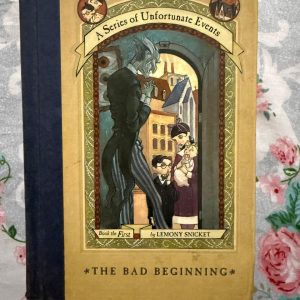 Used Book - A Series of Unfortunate Events - The Bad Beginning - Lemony Snicket - Illustrations by Brett Helquist - Harper Collins - Lemony SnicketтАЩs The Bad Beginning is a masterclass in gothic whimsy. With its darkly hilarious tone, ingenious wordplay, and Brett HelquistтАЩs wonderfully atmospheric illustrations, the book perfectly captures the Baudelaire orphans' plight. It is a delightfully bleak, captivating start to a beloved series that masterfully rewards clever, perceptive readers.